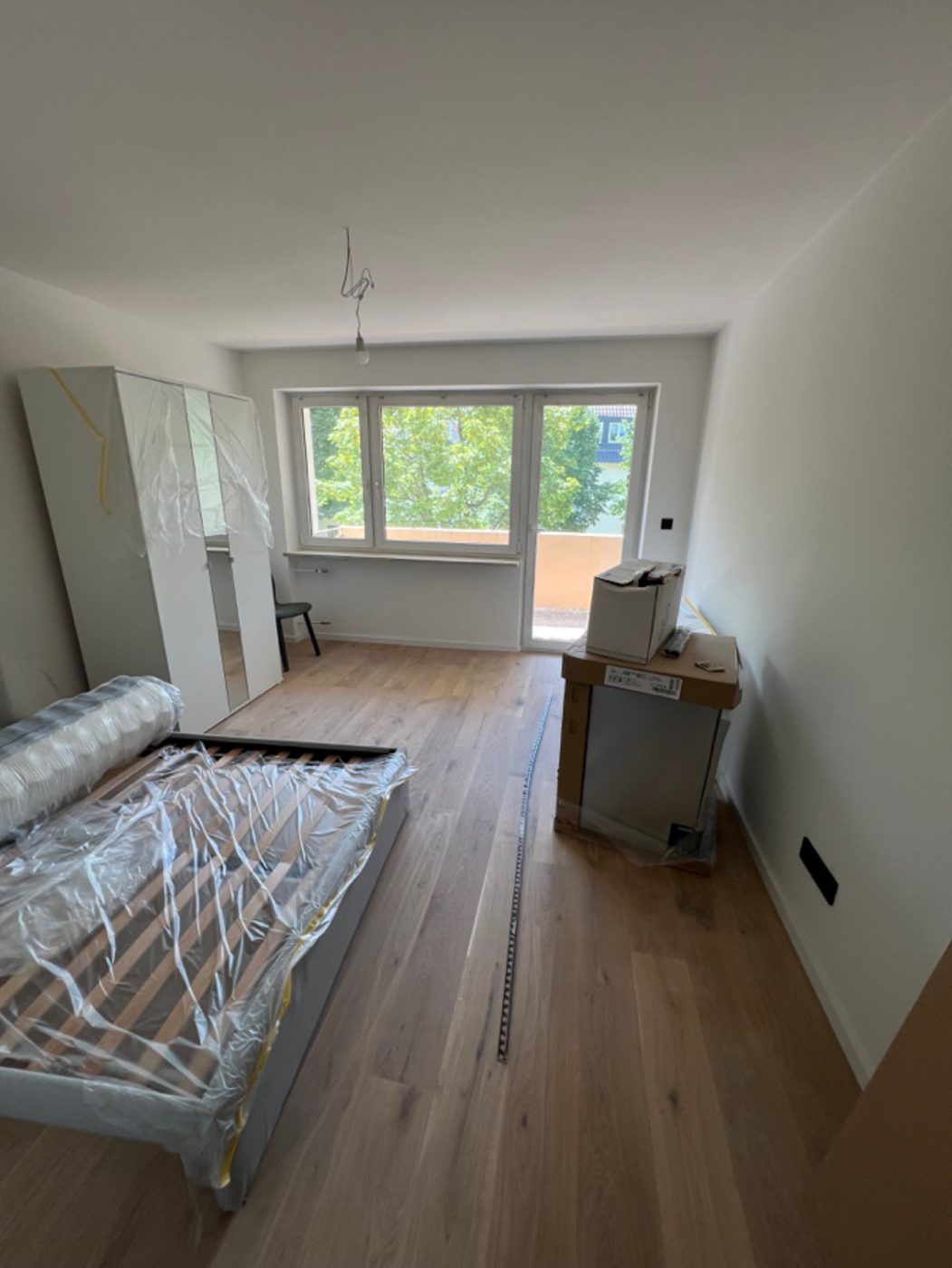 Zimmer in der Endmontage mit hochwertigem Boden und noch verpackten Möbeln